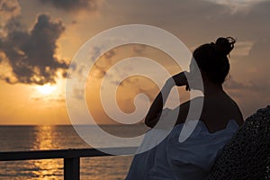 Silhouette of a beautiful woman contemplating sunrise from a balcony over the sea