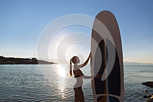 Silhouette of a beautiful woman on stand up paddle board. SUP, concept lifestyle, sport