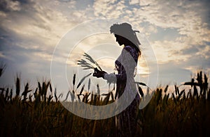 Silhouette of a beautiful woman in a wheat field at sunset