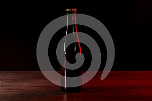 Silhouette of a beer bottle on a black background with red and orange lights