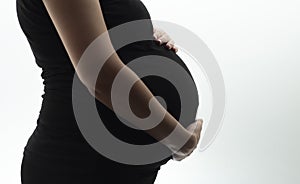 Silhouette of belly of pregnant woman hugging baby with hands on white isolated background