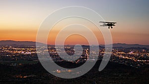 Silhouette of a bi-plane flying over Phoenix, AR