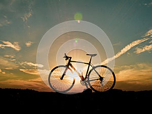 Silhouette of a bicycle parked on the beach in the evening