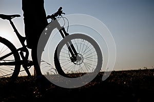 The silhouette of a bicycle and rider against the blue sky at sunset