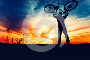 Silhouette of bicyclist rising bike and celebrating first place in contest