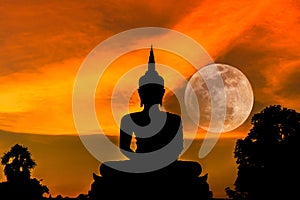 Silhouette big buddha statue on sunset with full moon background