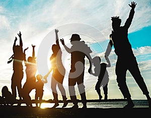 Silhouette of big family having fun on the beach at sunset - Father, mother, children and uncles enjoying time together - Focus on