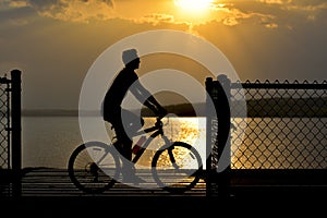 Silhouette of Bike Rider in Front of Sunset and Lake