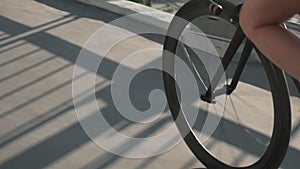 Silhouette of bike wheel in sunset light. Girl is pedaling bike, close up of bike gear. Cyclist is pedaling on bicycle at sunrise.