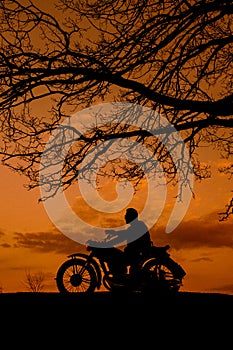 Silhouette of a biker with a cigarette against the background of the sunset.