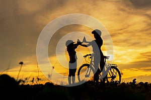 Silhouette biker lovely family at sunset over the ocean.  Mom and daughter bicycling chill and relax at the beach.