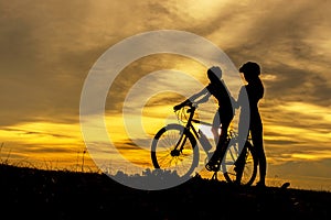 Silhouette biker lovely family at sunset over the ocean.  Mom and daughter bicycling chill and relax at the beach.