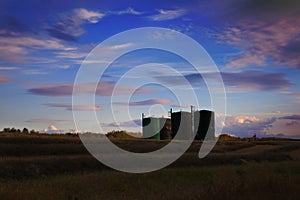 Silhouette of bitumen tanks under a sunset