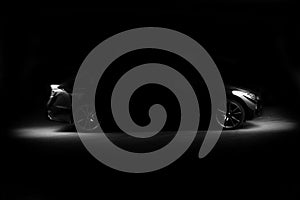 Silhouette of black sports car with headlights on black background