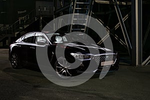 Silhouette of black sports car with headlights on black background