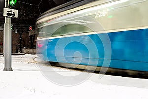 Silhouette of a blue tram in motion at a turn at night in winter