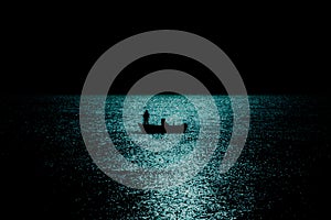 Silhouette of boat fishing in the sea in moonlight reflection reverse light