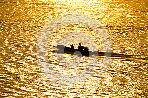 Silhouette of a boatman in river on golden sunshine