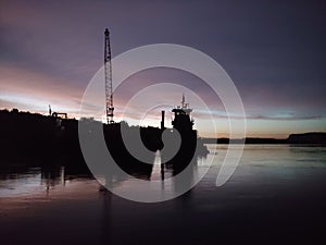 Silhouette of boats and equipment at dusk on the Mississippi River.