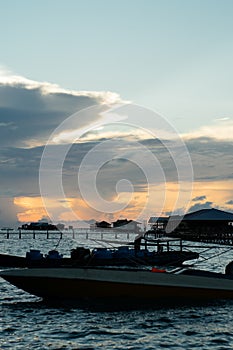 Silhouette of boats and unidentified man working early morning during sunrise.