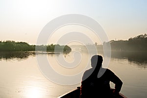 silhouette of boatsman rowing out into the yamuna ganga river in the morning