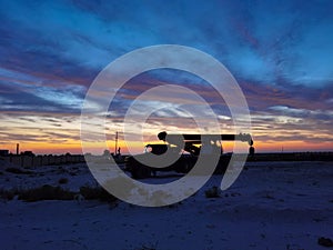 Silhouette of a Boom truck in the oilfield at sunset