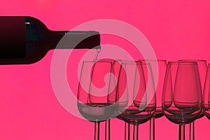 Silhouette of a bottle of wine that fills glasses on a pink background