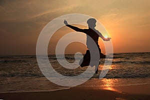 A boy jumps in the waves during sunset