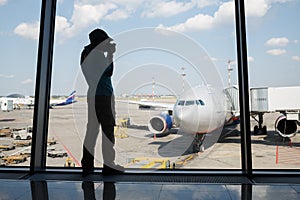Silhouette of a boy photographing a plane through