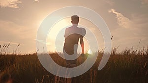 Silhouette of a boy playing football at sunset. A boy juggles a ball in the field at sunset