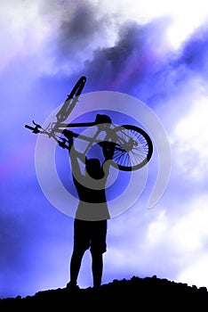 Silhouette of a boy riding a mountain bike blue sky