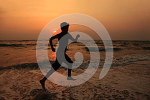 A boy runs along the beach during sunset