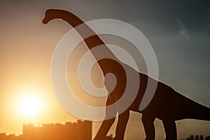 Silhouette of brachiosaurus and buildings in a sunset time