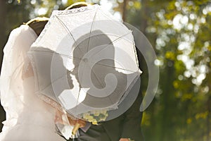 Silhouette of bride and groom behind lace parasol