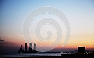 Silhouette of bridge connected offshore oil production platforms at oil field