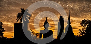 Silhouette of a Buddha statue and a temple at sunset