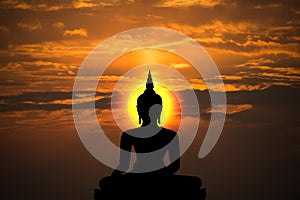 Silhouette of buddha and sunset background.