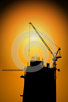 Silhouette Building construction site with cranes on high ground over sunset background