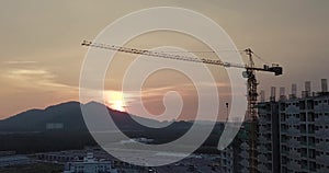 Silhouette of building under construction with crane during sunset, vintage filter