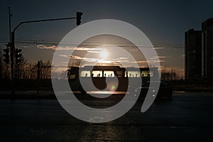 Silhouette of a bus in the background of the setting sun.