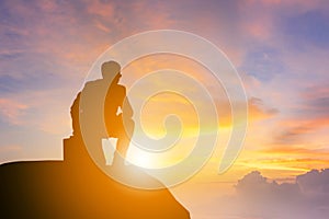 Silhouette of Business man kneeling position and looking forward on a mountain top Sunset Evening Sky Background, Success and acti