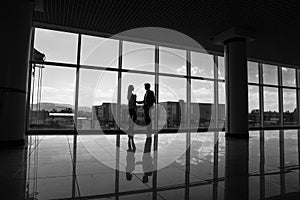 Silhouette of Businessman and Businesswoman shaking hands in office with big panoramic windows, Business concept.