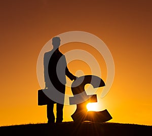 Silhouette of Businessman Holding Currency Sign