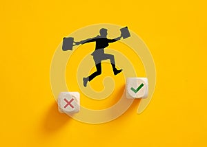 Silhouette of a businessman jumping from wrong cross symbol to right check mark symbol on wooden cubes