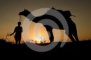 Silhouette of the Camel Trader crossing the sand dune .