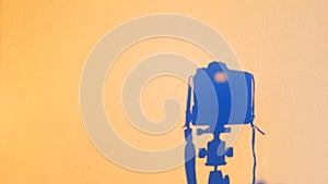 Silhouette of camera reflex on the wall at sunset, concept of technology photography