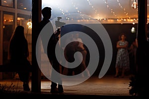 Silhouette of cameraman standing with video action film production digital camera at wedding, birthday party