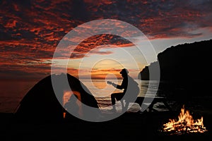 Couple camping with guitar and campfire on the beach