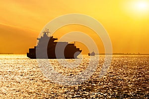 Silhouette of cargo ship with full shipload cargo containers are sailing in the Osaka bay evening