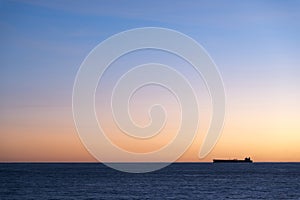 Silhouette of cargo ship on the horizon